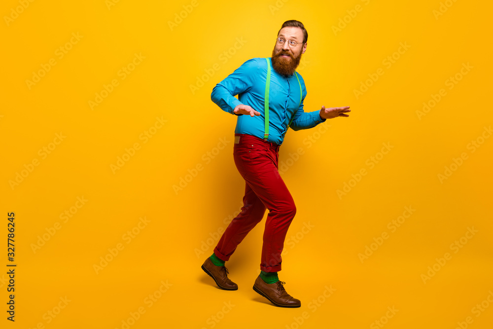 Full length photo of attractive guy slow hush steps hiding girlfriend making surprise visit wear blue shirt green suspenders red pants socks footwear isolated yellow color background Full length photo of attractive guy slow hush steps hiding girlfriend making surprise visit wear blue shirt green suspenders red pants socks footwear isolated yellow color background