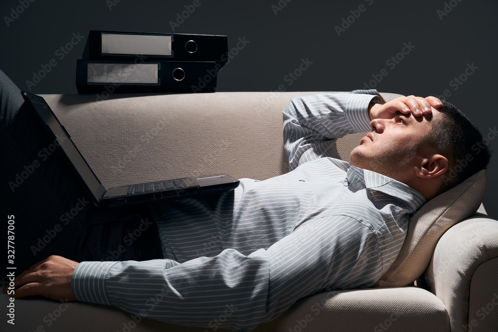 Fototapeta premium businessman is lying on the sofa with laptop and resting