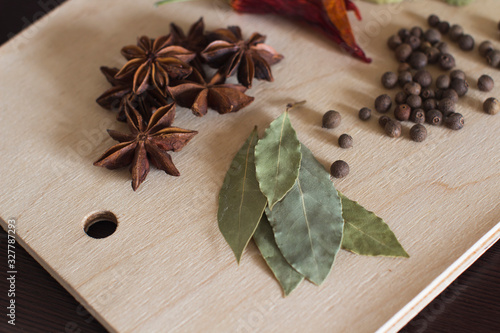 black aroma pepper, anis, dry hot red pepper and bay leaf on a wooden cutting board on a kitchen table