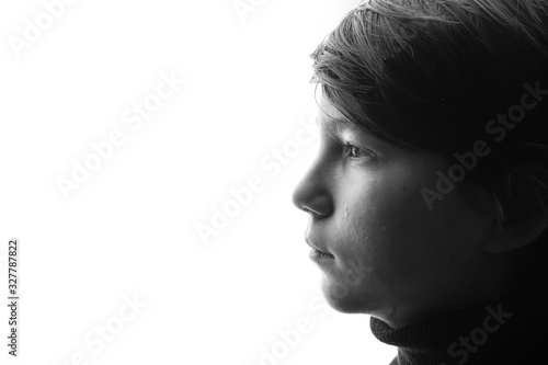 Black and white portrait of young sad boy crying with sad eyes. White background. Free space for text. Tear on cheek of unhappy teenager. © KDdesignphoto