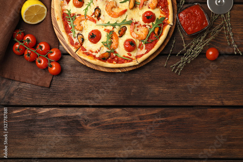 Delicious seafood pizza on wooden table, flat lay. Space for text