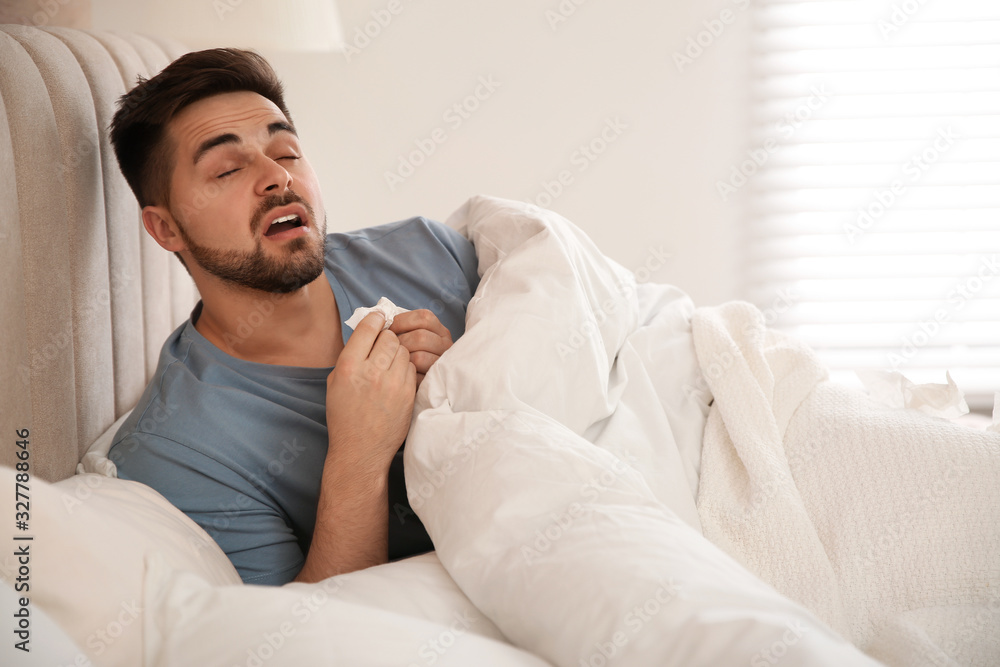 Sick young man in bed at home. Influenza virus Sick young man in bed at home. Influenza virus