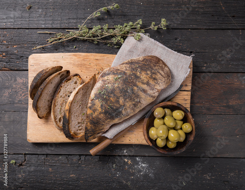  Fresh italian ciabatta bread  for leaven with herbs, olives on wooden background, top view, copy space. photo