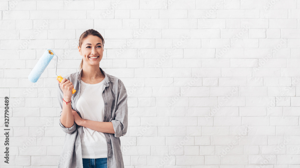 Young woman holding paint roller for renovation at home Young woman holding paint roller for renovation at home