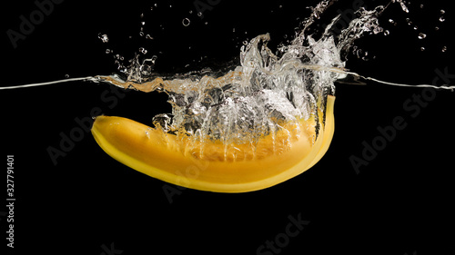 Yummy banana flying deep into water against black background, panorama