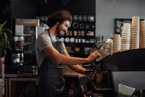Smiling man with apron preparing coffee for customer in his small business photo
