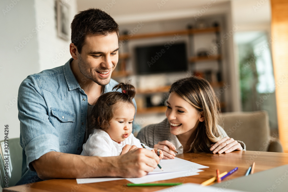 Young happy parents coloring with their small daughter at home. Young happy parents coloring with their small daughter at home.