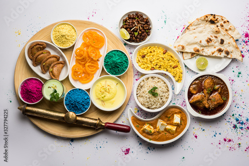 Happy Holy concept  showing Indian assorted lunch food like chicken, paneer butter masala, naan, jeera rice, black chana fry, jalebi, fujiyama, thandai and Farsan with holi colours and pichkari  photo