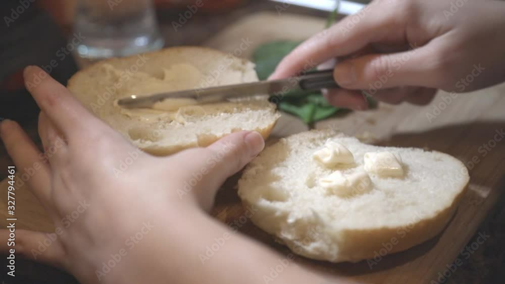 Spreading the mayonnaise on top of the half sliced sandwich bun - closeup shot Spreading the mayonnaise on top of the half sliced sandwich bun - closeup shot