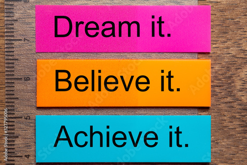 Wallpaper Mural Three bookmark stickers with the words dream it, believe it, achieve it, on a dark natural wooden table Torontodigital.ca