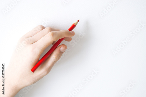 red pencil in left hand on paper background