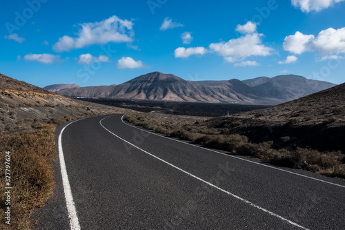 Endless road to Timanfaya National park in Lanzarote, Canary Ispands, Spain, Europe, Africa. Volcanic, black sand, harsh, tough, inhospitable, dry, sub-tropical, desert landscape.