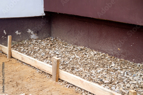 Repair of the blind area at the apartment building. Preparation for pouring concrete. Covered with gravel. Casing made of boards.
