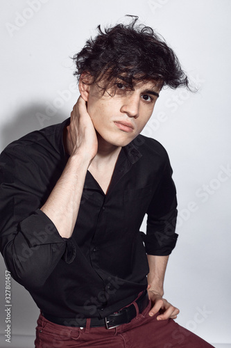 Young guy in a black shirt similar to Adriano Celentano posing on a white background. Fashion portrait photo