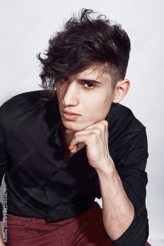Young guy in a black shirt similar to Adriano Celentano posing on a white background. Fashion portrait Young guy in a black shirt similar to Adriano Celentano posing on a white background. Fashion portrait
