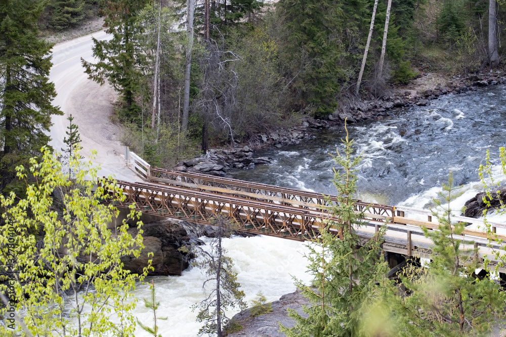 Aerial view of a bridge over a river in the Canadian Rockies during a vibrant sunny summer day. Located in British Columbia, Canada