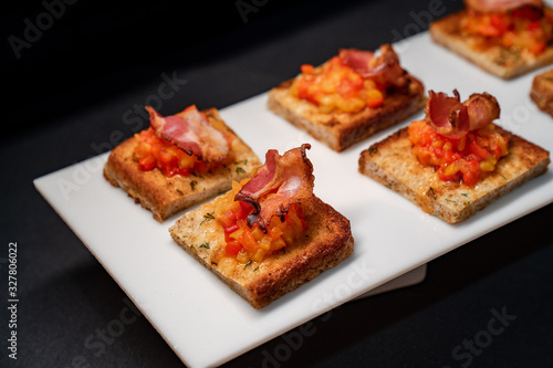 toast with vegetables and bacon, black background.