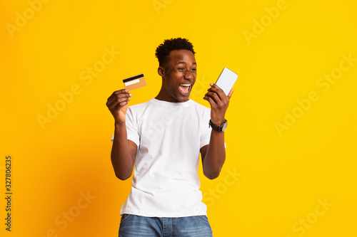 Young excited african guy making money online with cell phone