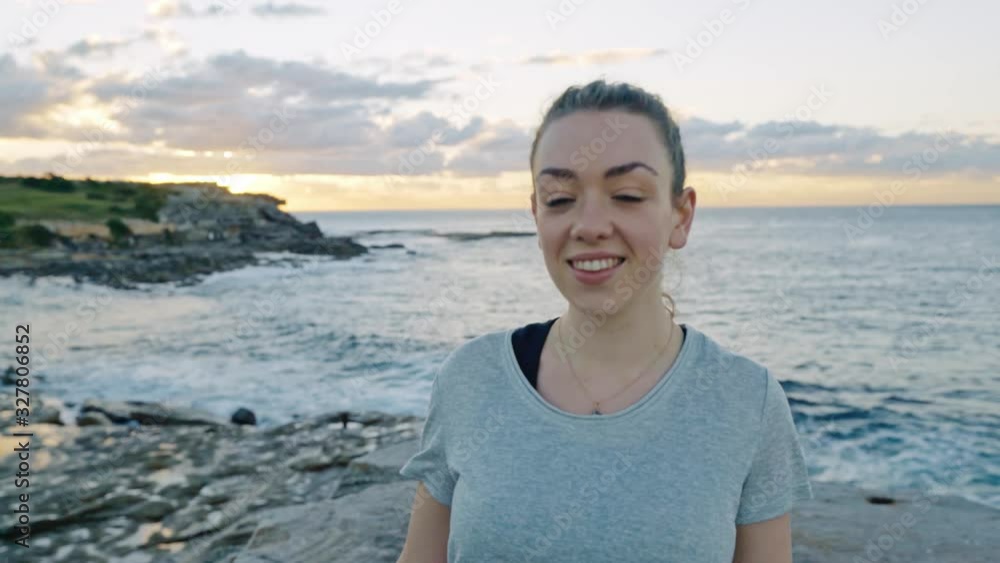 Pretty young girl walks towards the camera smiling as the sun peaks over the cliffs of Clovelly Beach, Sydney, Australia. Pretty young girl walks towards the camera smiling as the sun peaks over the cliffs of Clovelly Beach, Sydney, Australia.
