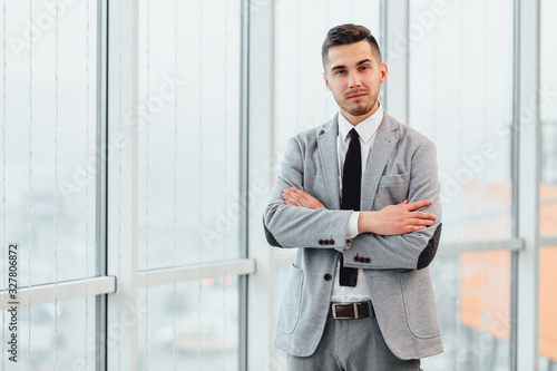 Fényképezés Confident young businessman standing with his hands folded, looking at the camera, ready to hard work day