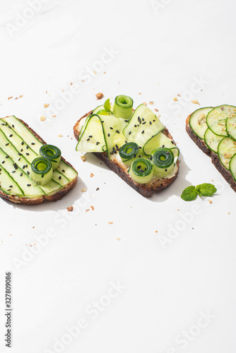 Tableau sur toile fresh cucumber toasts with seeds, mint leaves on white background