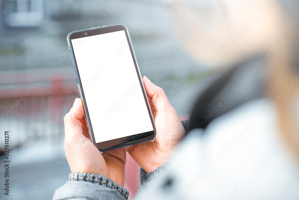 Hand holds a smartphone with a white screen. Blank mobile phone mockup Hand holds a smartphone with a white screen. Blank mobile phone mockup