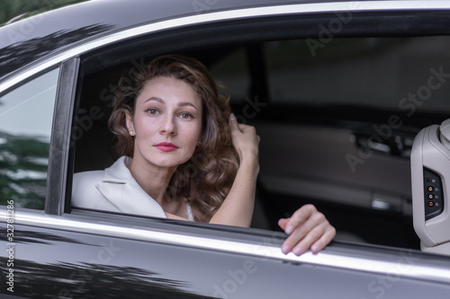 Attractive woman with curly hairstyle sitting in car