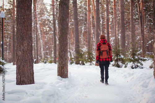Male tourist with backpack walks on snow pine forest. Guy hiking at nature. Concept of winter holiday or vacation..