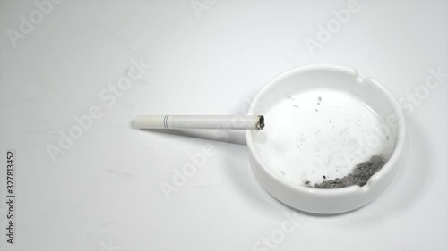 Wind blows off image skull from ash inside ashtray. Cigarette on ashtray. photo