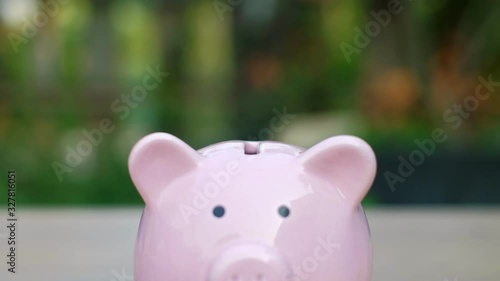 Close up Hand is putting a coin in a piggy bank with bokeh background. finance and business concept.