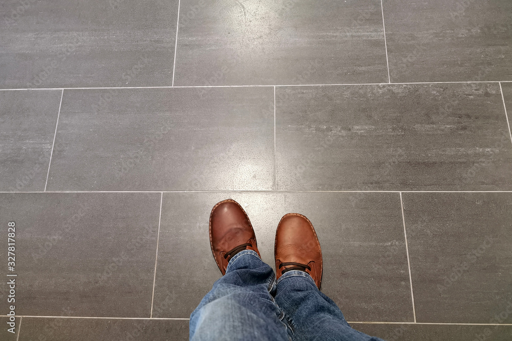 Legs in jeans and red shoes against the background of the tiled floor - obrazy, fototapety, plakaty 