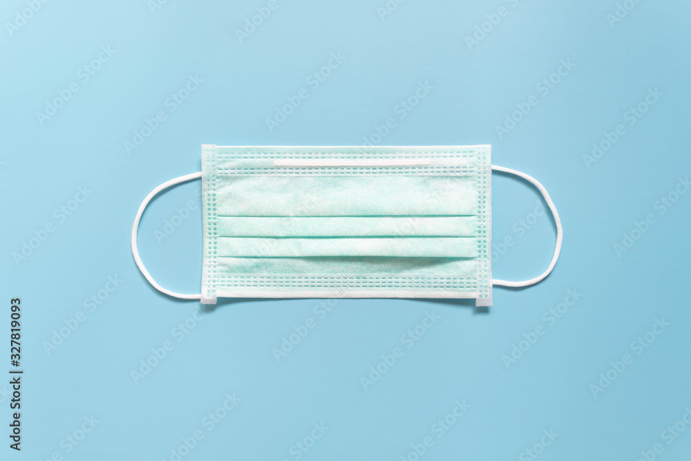 Protective medical face mask on light blue background. Devices designed to protect the wearer from inhaling airborne bacteria, virus or dust particles. Health care. Top view. Protective medical face mask on light blue background. Devices designed to protect the wearer from inhaling airborne bacteria, virus or dust particles. Health care. Top view.