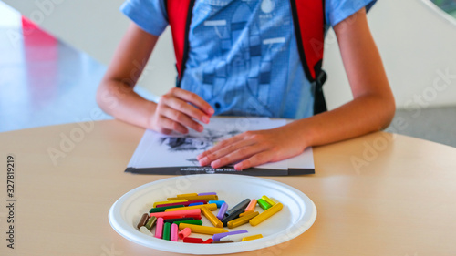 Boy draws with colored wax crayons