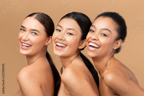 Three Diverse Models Smiling To Camera Posing Over Beige Background
