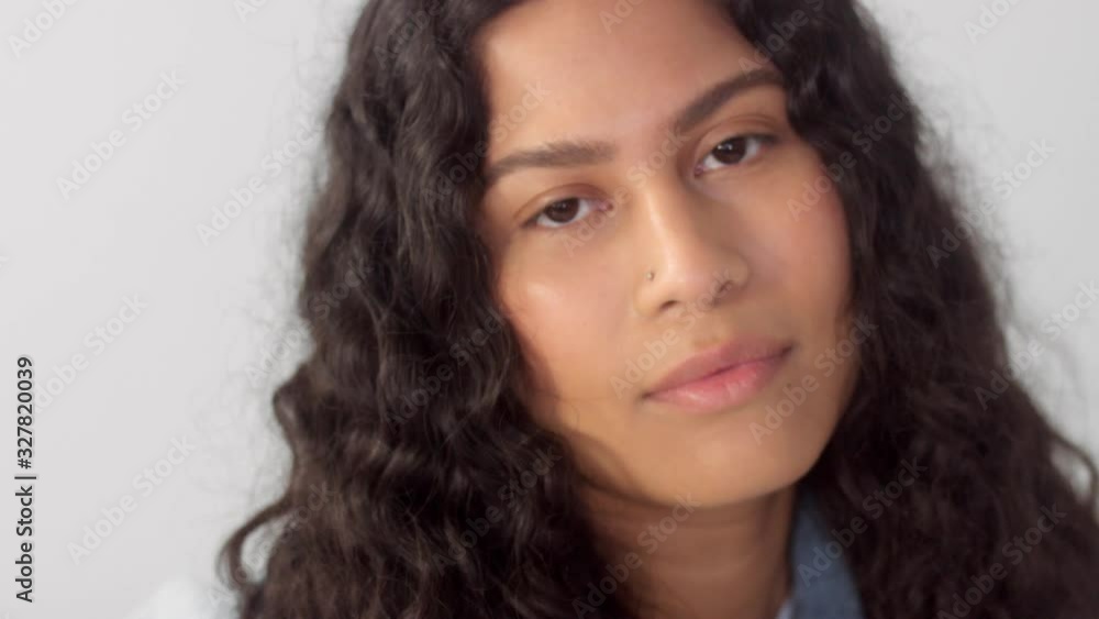 Closeup portrait of native american mixed race plus size woman touches her curly hair and watching to the camera Closeup portrait of native american mixed race plus size woman touches her curly hair and watching to the camera