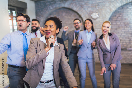 Funny teambuilding indoors activity. Business people making team training exercise during team building seminar singing karaoke.