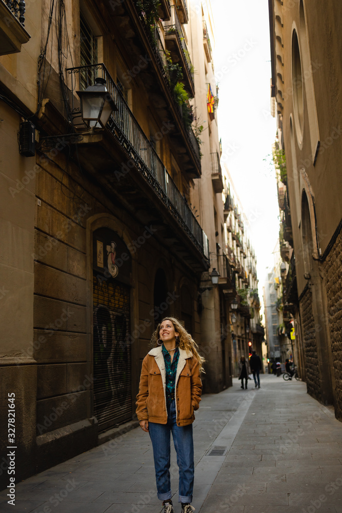 Girl walking through the streets in Barcelona. Cute girl with blond curly hair walking through the streets on Barcelona looking at the buildings and doing tourism