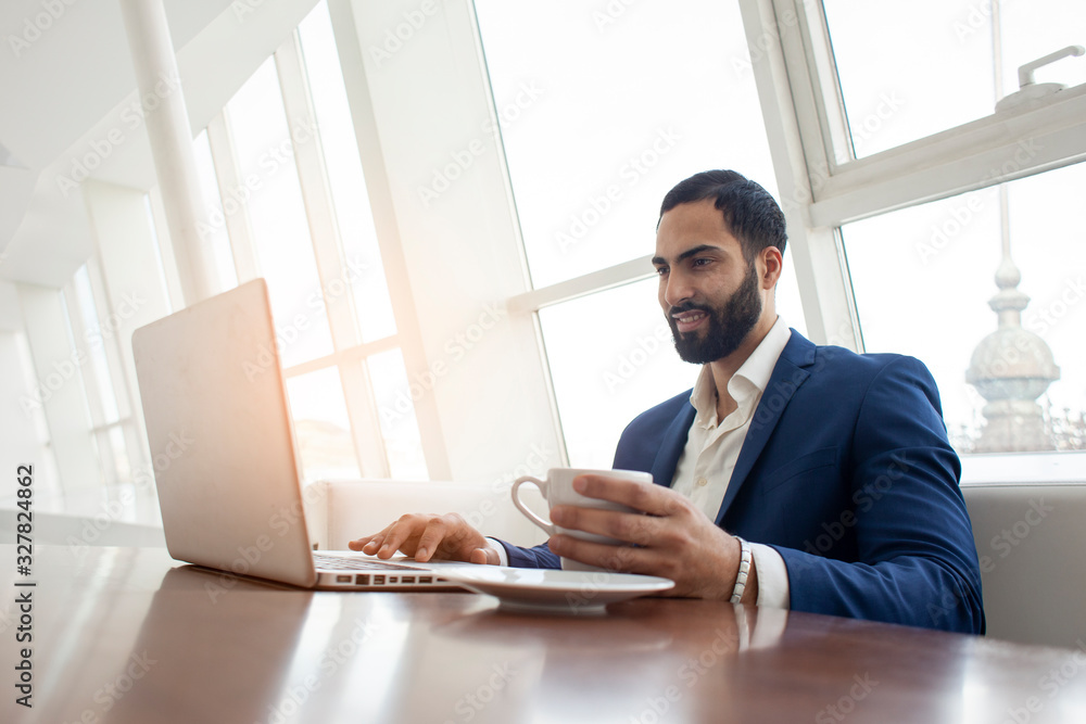 young successful businessman use a laptop and drink coffee in the morning at cafe, a freelancer is sitting with a computer in a office young successful businessman use a laptop and drink coffee in the morning at cafe, a freelancer is sitting with a computer in a office