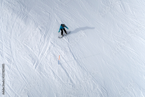 Freeride snowboarder going downhill on snow background. Aerial view.