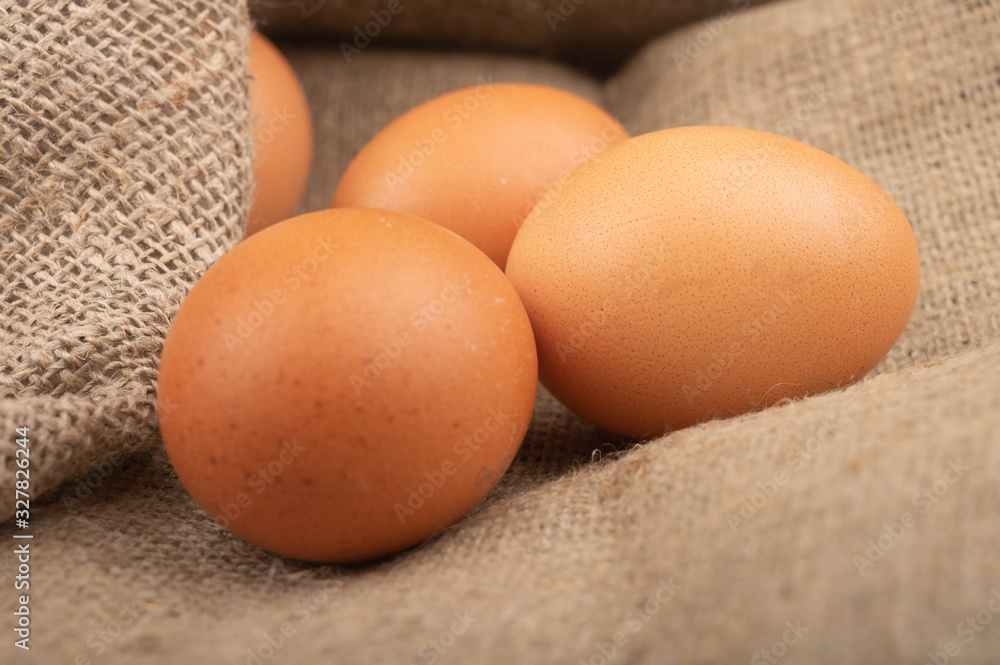 Chicken eggs on a background of rough homespun fabric. Homemade preparations, rustic treats. Close up. Chicken eggs on a background of rough homespun fabric. Homemade preparations, rustic treats. Close up.