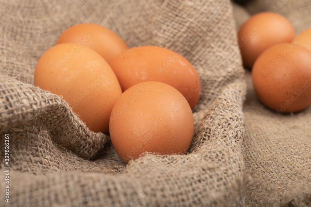 A few chicken eggs on a background of rough homespun fabric. Country food. Close up. A few chicken eggs on a background of rough homespun fabric. Country food. Close up.