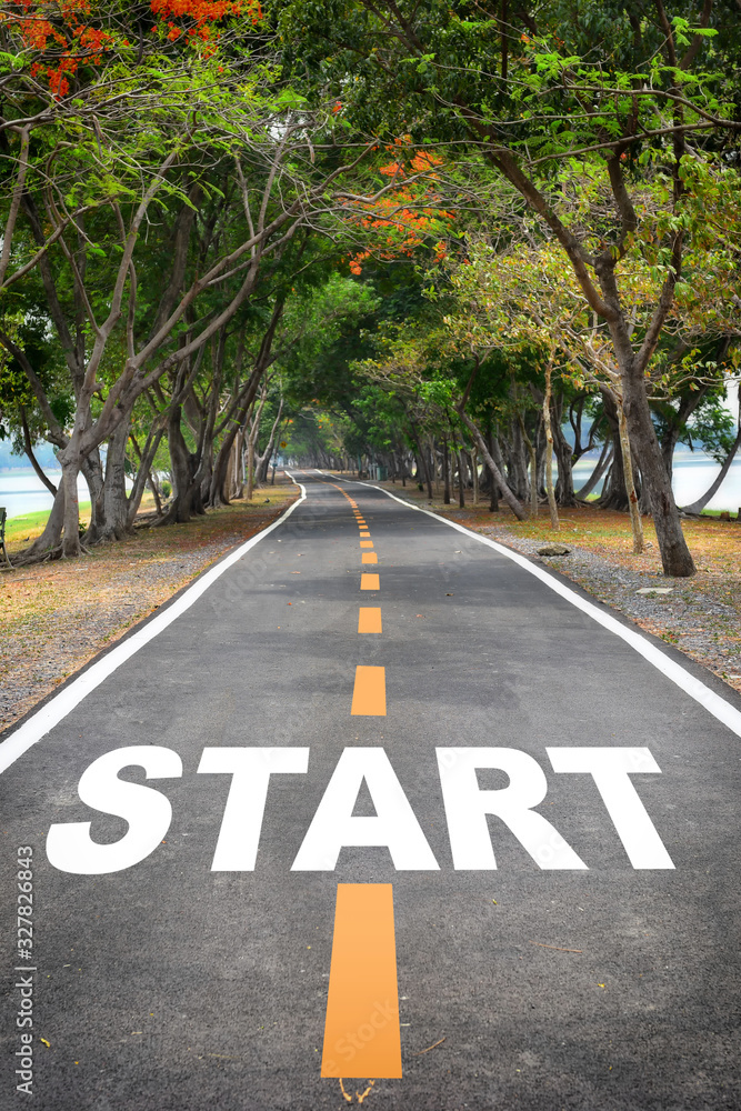 Obraz premium Tree tunnel with start word on asphalt road surface, business success concept and natural idea