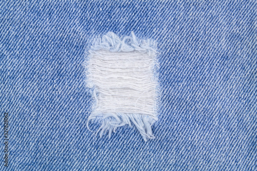 Fototapeta Blue denim jeans textile with hole close up