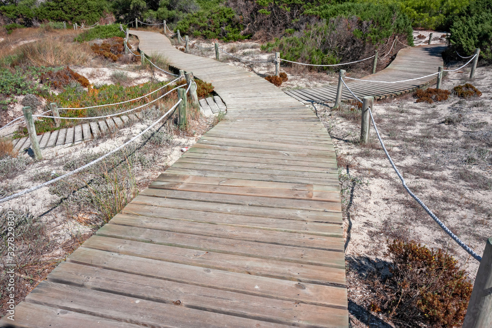 A wooden walkway allows you to walk the beautiful dunes on the coast of Formentera in the Balearic islands of Spain.