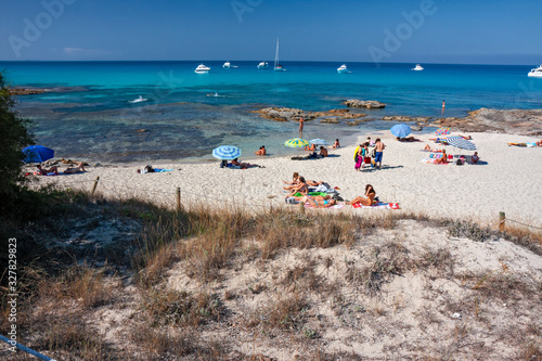 Bathers sunbathing in the wild and sunny beaches of Formentera in the Balearic islands of Spain.