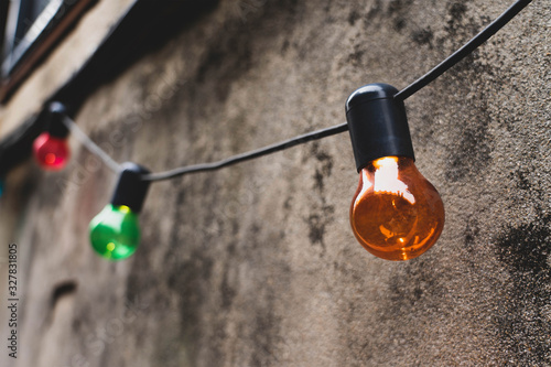 Decorative light bulbs hanging on a wall in an alley.