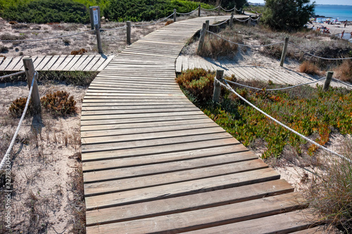 A wooden walkway allows you to walk the beautiful dunes on the coast of Formentera in the Balearic islands of Spain.