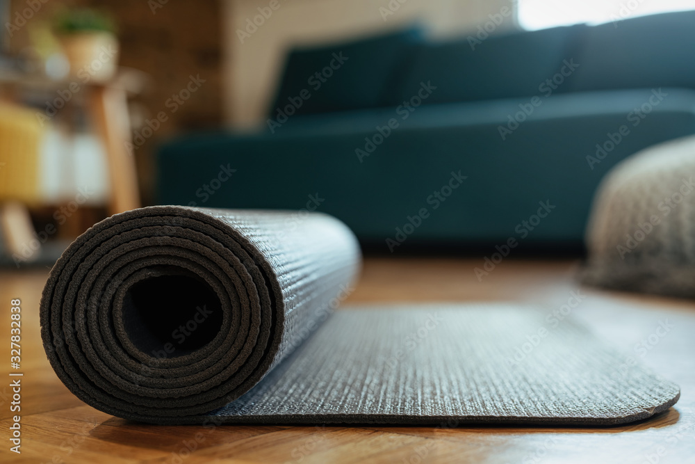 Close-up of rolled exercise mat on parquet floor. - obrazy, fototapety, plakaty 