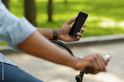 Afro man riding bike and using smartphone with black screen