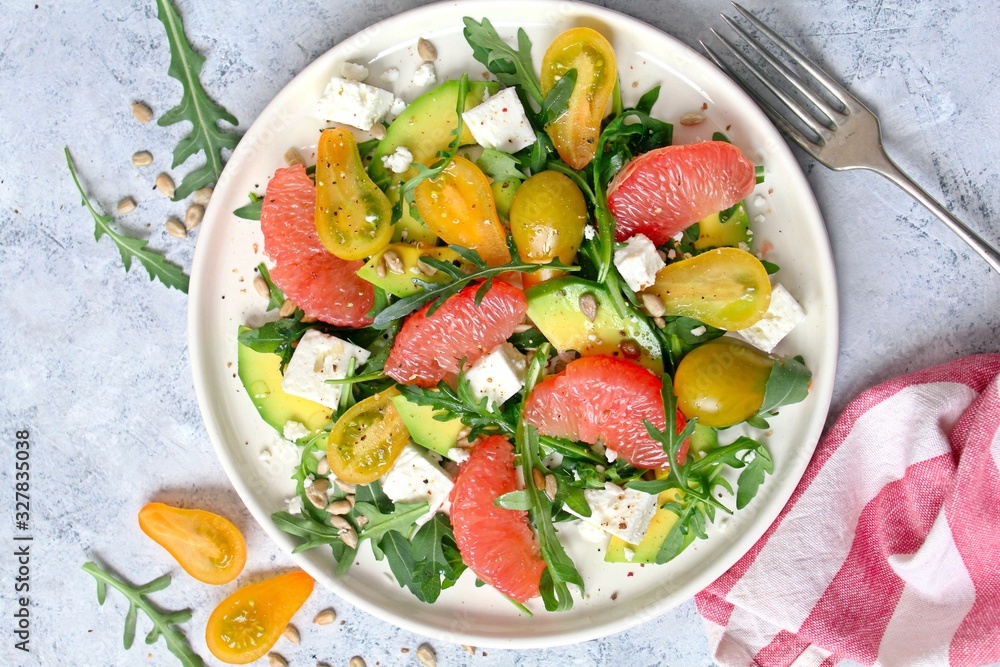 Avocado salad with grapefruits, tomato, feta cheese, arugula and sunflower seeds. Top view with copy space. Healthy eating. Avocado salad with grapefruits, tomato, feta cheese, arugula and sunflower seeds. Top view with copy space. Healthy eating.